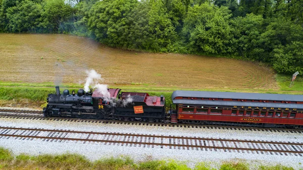 Ariel görünümünü bir Buhar yolcu treni çekerek piknik alanı üfleme duman içine yaz bir dron tarafından görüldüğü gibi güneşli bir