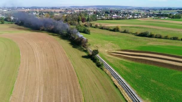 ドローンで見られるように アーミッシュ カントリー サイドに沿って煙を吹きかける蒸気旅客列車の航空写真 — ストック動画