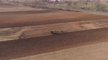 Amish çiftliği çalışanı havadan görünümü bir drone tarafından görüldüğü gibi erken baharda alanı tornalama