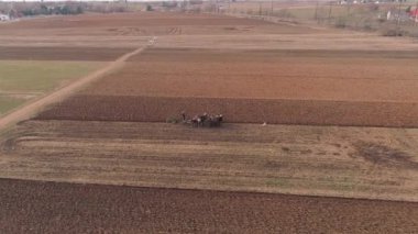 Amish çiftliği çalışanı havadan görünümü bir drone tarafından görüldüğü gibi erken baharda alanı tornalama