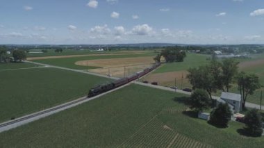 Strasburg, Pennsylvania, Haziran 2019 - Bir Drone tarafından görüldü olarak Güneşli Bir Yaz Günü Boyunca Kabarık Bir Vintage Buharlı Tren ile Farmlands ve Kırsal Havadan Görünümü