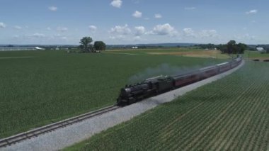 Strasburg, Pennsylvania, Haziran 2019 - Bir Drone tarafından görüldü olarak Güneşli Bir Yaz Günü Boyunca Kabarık Bir Vintage Buharlı Tren ile Farmlands ve Kırsal Havadan Görünümü