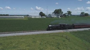 Strasburg, Pennsylvania, Haziran 2019 - Bir Drone tarafından görüldü olarak Güneşli Bir Yaz Günü Boyunca Kabarık Bir Vintage Buharlı Tren ile Farmlands ve Kırsal Havadan Görünümü