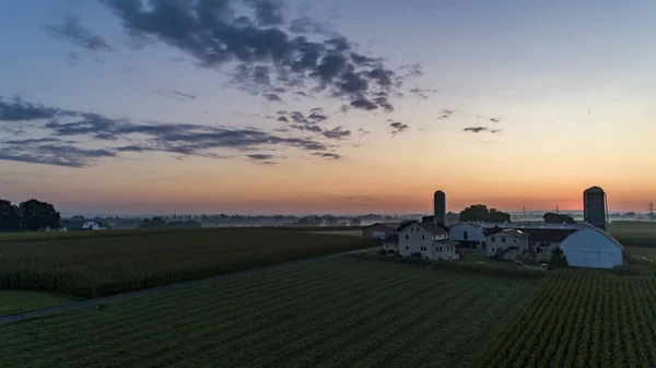 Sonnenaufgang über einem amischen Bauernhof mit Blau- und Rottönen mit Heißluftballon — Stockfoto