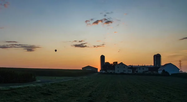 Wschód słońca nad Amish Farm z Blues i czerwone z gorącym powietrzem balon — Zdjęcie stockowe