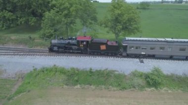 Ronks, Pennsylvania, Temmuz 2019 - Bir Drone tarafından görüldü olarak Güneşli bir Yaz Günü Amish Kırsal Boyunca Seyahat Yolcu Tren Puffing Duman ile 1910 Buhar Motoru Havadan Görünümü