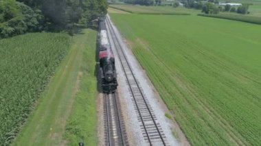 Ronks, Pennsylvania, Temmuz 2019 - Bir Drone tarafından görüldü olarak Güneşli bir Yaz Günü Amish Kırsal Boyunca Seyahat Yolcu Tren Puffing Duman ile 1910 Buhar Motoru Havadan Görünümü