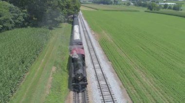 Bir Drone tarafından görüldü olarak Güneşli Bir Yaz Günü Amish Kırsal Boyunca Seyahat Yolcu Tren Ipuffing Duman ile 1910 Buhar Motoru Havadan Görünümü