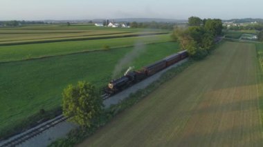 Ronks, Pennsylvania, Temmuz 2019 - Amish Kırsalı Boyunca Seyahat Eden Yolcu Treni ile 1924 BuharLı Motorun Havadan Görünümü, Bir Drone'un Gördüğü Bir Yaz Günü Gün Batımı olarak