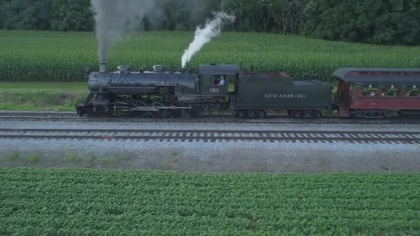 ロンクス ペンシルベニア州 2019年7月 ドローンが見た夏の日の夕日としてアーミッシュの田園地帯を走行する旅客列車を持つ1924年蒸気機関の航空写真 — ストック動画