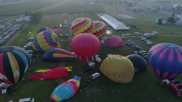 晴れた夏の朝のバルーンフェスティバルで離陸する日の出熱気球の航空写真 — ストック動画