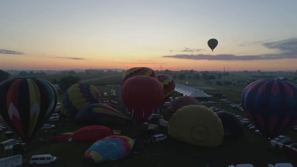 晴れた夏の朝のバルーンフェスティバルで離陸する日の出熱気球の航空写真 — ストック動画