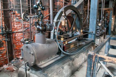 Tarihi bir buhar makinesi, karmaşık tasarımı ve metal borularını sergileyen endüstriyel makineler arasında yer alıyor..