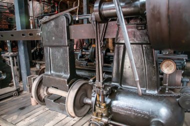 Ağır metal makineleri, karmaşık ayrıntılar ve mekanik bileşenleriyle tarihi bir fabrikada sergilenmektedir..