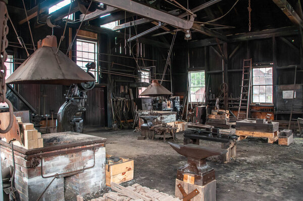 The interior of a vintage blacksmith workshop showcases various tools and equipment.
