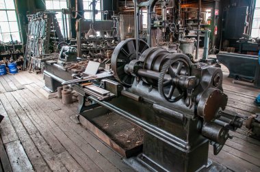 Çeşitli aletler ve makinelerle dolu eski bir atölye çalışması. Çalışan bir endüstriyel torna..