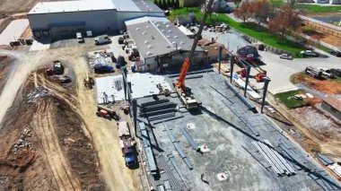 Gordonville, Pennsylvania, 4-9-2025 - Construction site in rural area shows active work with crane lifting materials. Workers are busy on the framework of new building, surrounded by fields and homes.