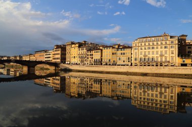 Florence, İtalya - 24 Eylül 2017: Floransa, İtalya akşam ışığında Arno Nehri'nin su 24 Eylül 2017 üzerinde yansıyan Ponte Santa Trinita Köprüsü'nde insanlar yürümek