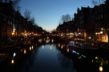 Amsterdam, Hollanda - 3 Şubat 2017: Bir kanal ve akşamları, Amsterdam, Hollanda 3 Şubat 2017 üzerinde bir kafede oturan insanlar boyunca tarihi evleri