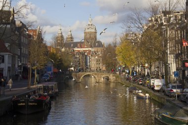 Amsterdam, Hollanda - 12 Kasım 2015: İnsanlar bir köprüde bir kanal ve uçan martı üzerinde arka planda Aziz Nikolaos Kilisesi ile sonbaharda 12 Kasım 2015 Amsterdam, Hollanda yürüyüş.