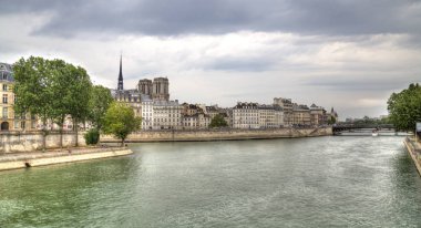 Paris, Fransa - 12 Mayıs 2018: kulelerin Notre Dame ve Paris, Fransa'da Seine Nehri'nin üzerinde 12 Mayıs 2018 üzerinde oturan insanlar da dahil olmak üzere tarihi binalar