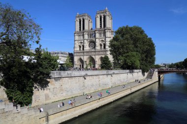 Paris, Fransa - 12 Mayıs 2018: Notre Dame Katedrali ve Paris, Fransa'da Seine Nehri'nin üzerinde 12 Mayıs 2018 üzerinde oturan insanlar