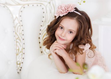 Portrat of a little girl with beautiful long dark hair, dressed in a light dress and a wreath on her head. clipart