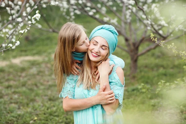 Portrait of kissing and happy mother and daughter in spring white garden. — Stock Photo, Image