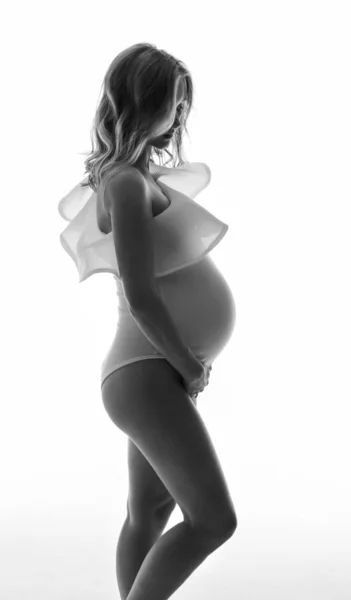 Chica embarazada en ropa interior blanca sobre un fondo claro —  Fotos de Stock