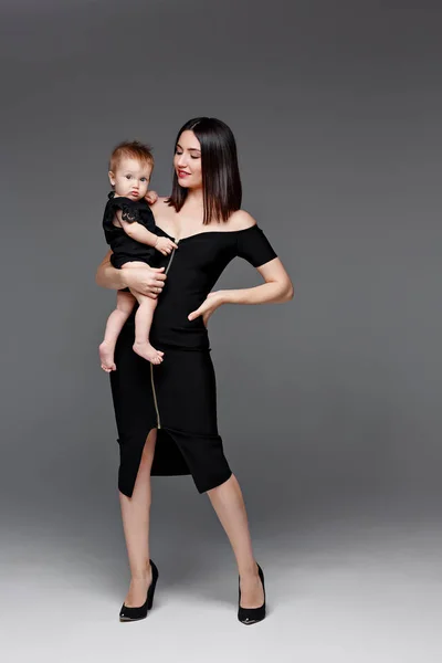 Jeune mère élégante en robe noire jouant avec une petite fille-bébé — Photo