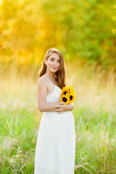 Bella ragazza incinta felice sul campo di fiori di margherita in luci del tramonto . — Foto Stock