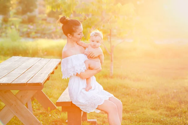 Mom is nursing her child in nature. Happy family sitting on the sunset background. — Stock Photo, Image
