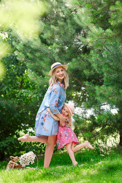 Pregnant mother with her daughter hugging in the park on a sunny summer day. The concept of happy motherhood and pregnancy. Family look. — Stock Photo, Image