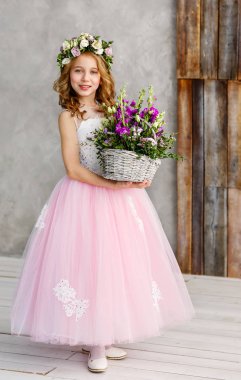 Kafasında taze çiçekler bir çelenk ve elinde güzel bahar çiçekleri bir sepet güzel sevimli küçük kız Dikey portre