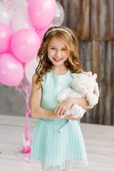 Pequena menina bonito em vestido bonito styot em um estúdio brilhante e segurando um brinquedo macio. Conceito de feliz aniversário — Fotografia de Stock