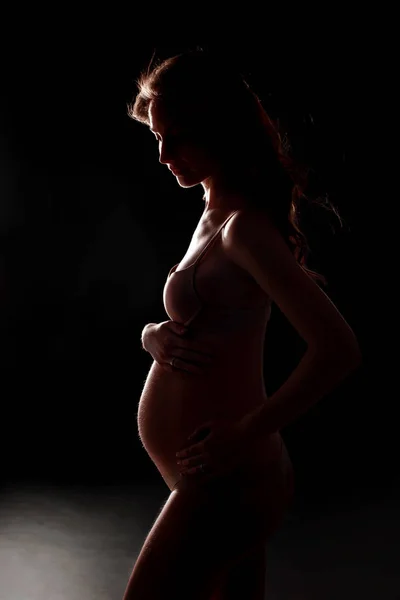 Silhouette incinta su sfondo nero. Concetto di gravidanza felice e maternità — Foto Stock