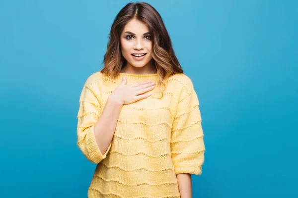 Mujer joven atractiva en suéter amarillo posando sobre fondo azul . — Foto de Stock