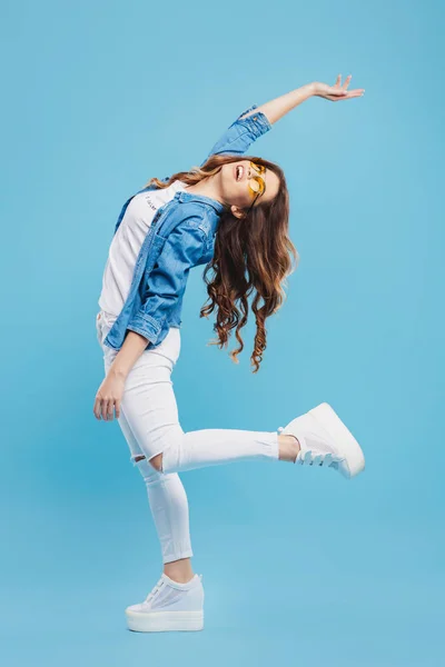 Mavi arka plan üzerinde poz çekici genç kadın. Güzel kız eğleniyor.