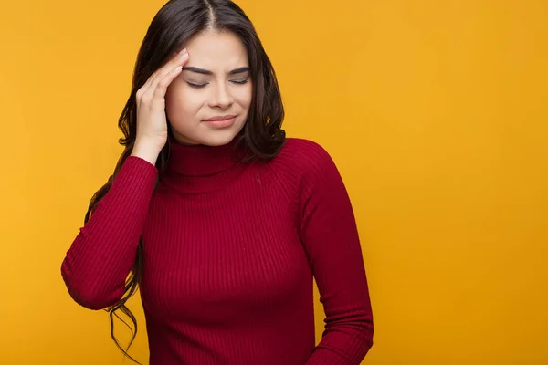 Young woman got sick and headache on orange background.