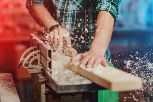 Tischler sägt mit der Kreissäge ein Holzbrett auf einem Holztisch in der Werkstatt. — Stockfoto