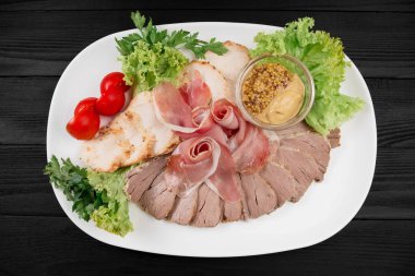 Siyah ahşap zemin üzerine beyaz bir tabakta et dilimlenmiş.