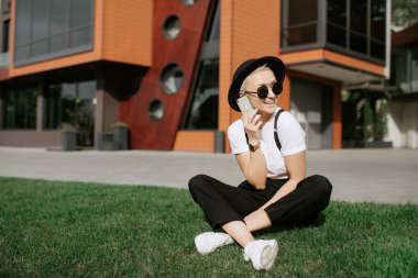 Çekici başarılı kadın kişi kentsel ayarda yürürken cep telefonu üzerinde arkadaşlarınızla konuşurken şık kıyafeti giymiş. Boş vaktinizi Street becerikli alet ile neşeli hippi kız.