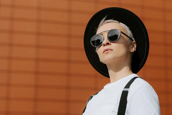 Aantrekkelijke trendy hipster jonge vrouw verblijf in de buurt van de muur. — Stockfoto