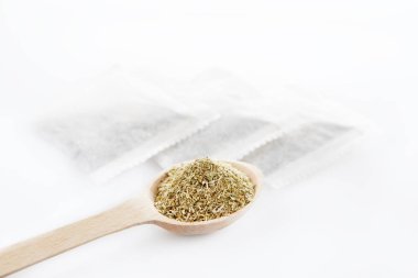 Tahta kaşık ve çay poşetleri beyaz arka plan üzerinde Şifalı Bitkisel çay yaprakları. Sağlık ve güzellik kavramı.