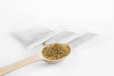 Tahta kaşık ve çay poşetleri beyaz arka plan üzerinde Şifalı Bitkisel çay yaprakları. Sağlık ve güzellik kavramı.