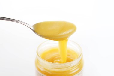 Beyaz bir arka plan üzerinde gümüş kaşıkla tatlı bal kavanozu. Sağlık ve güzellik kavramı.