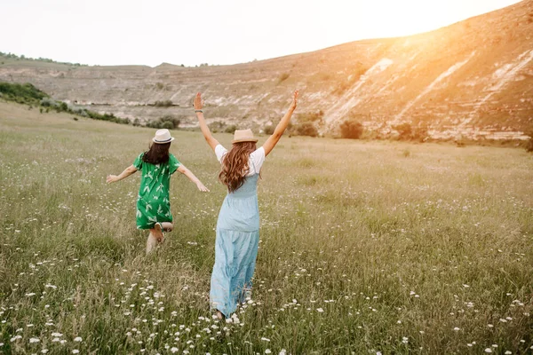 2 魅力的な幸せな若い女夕暮れの山を花が畑の上を歩いてします。Fredoom のコンセプトです。背面図. — ストック写真