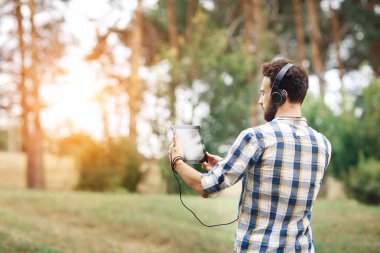 Tablet ve parkta müzik dinlerken kulaklık ile hippi Genç sakallı.