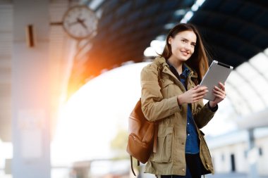 Tren İstasyonu platformu üzerinde duran tablet kullanma sırt çantası olan kadın.