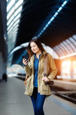 Tren İstasyonu platformu üzerinde duran akıllı telefon kullanan güzel genç kadın.